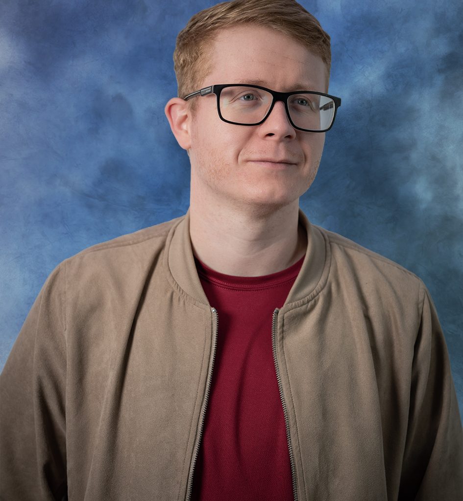 young man neatly dressed posing with blue backdrop